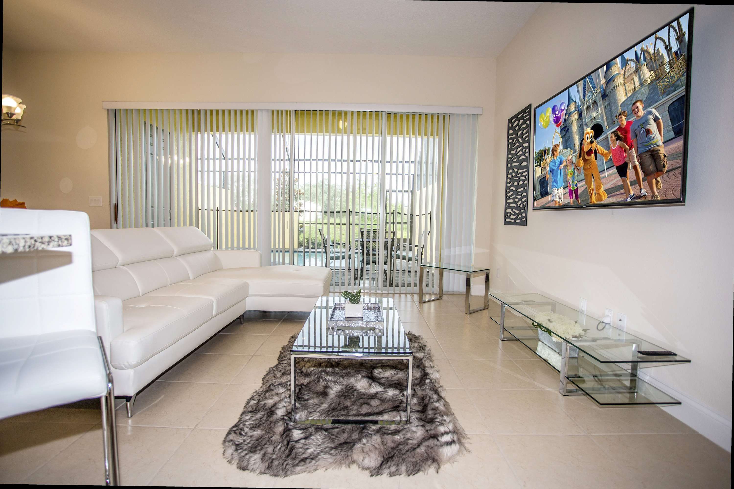A modern living room with a white sofa, a glass coffee table, and a fur rug.