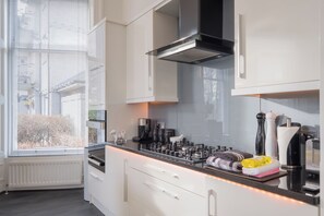 Enjoy cooking in this well-lit kitchen with an oven, coffee station, and stainless steel range hood.