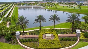 A resort with a central water feature, palm trees, and well-maintained lawns.