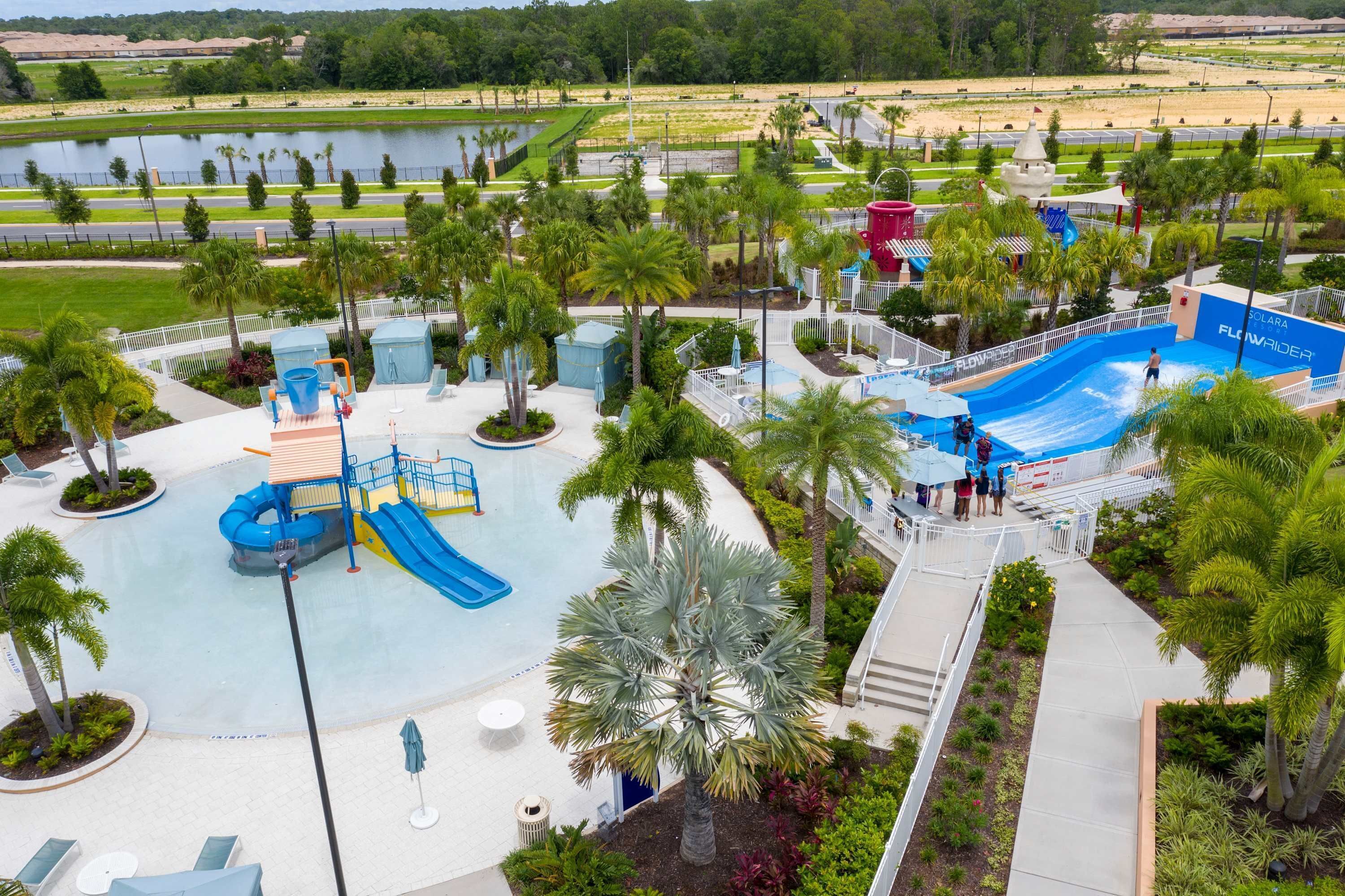 A water park with a large pool, slides, and palm trees.