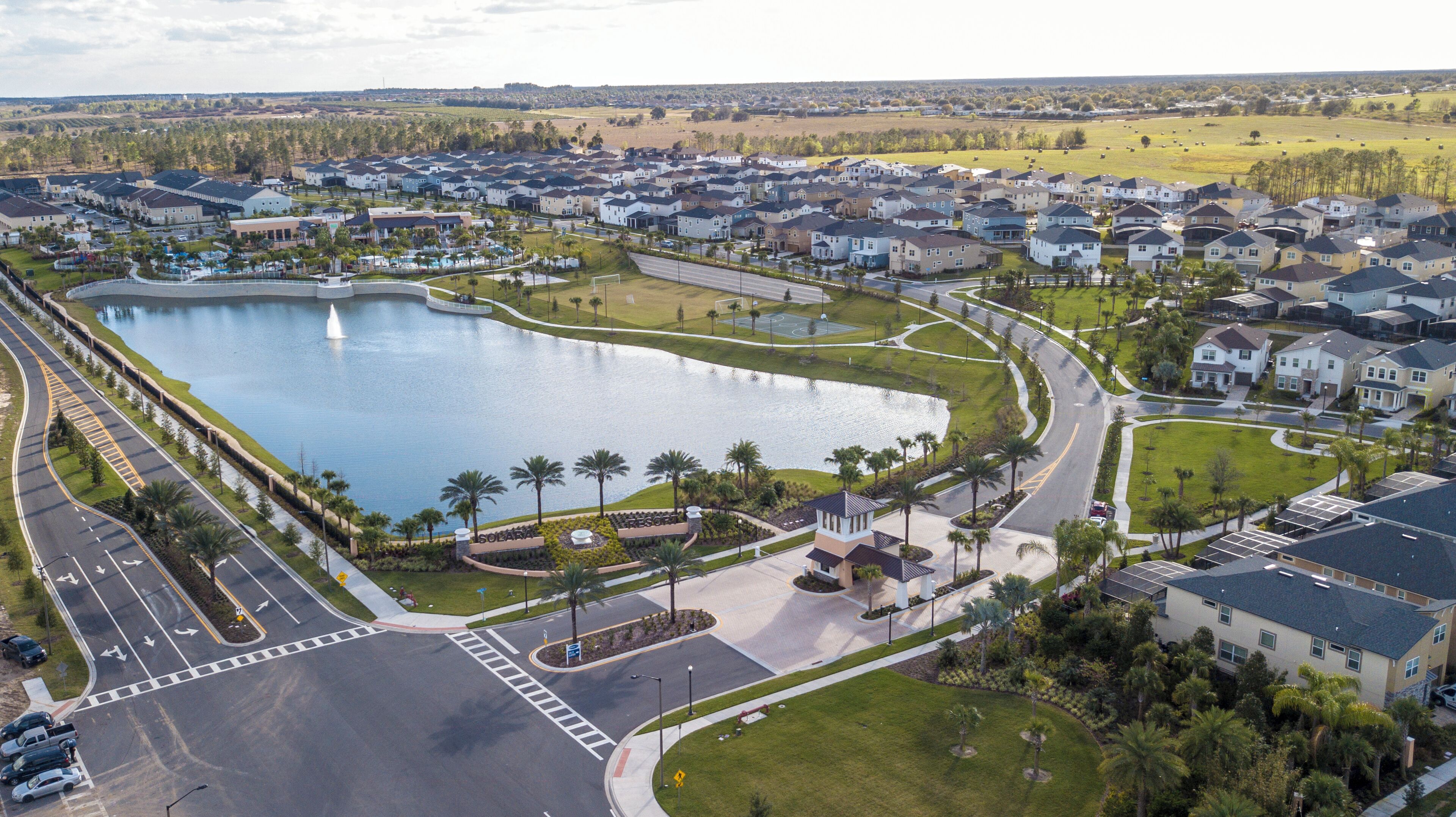 An aerial view of a residential area with a large lake, curved roads, and houses.