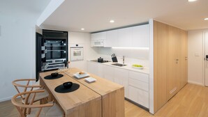 Een moderne keuken met witte kastjes, een houten eiland en een inbouwoven.