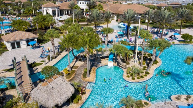 Un resort con una piscina grande, palmeras y una cabaña de techo de paja.