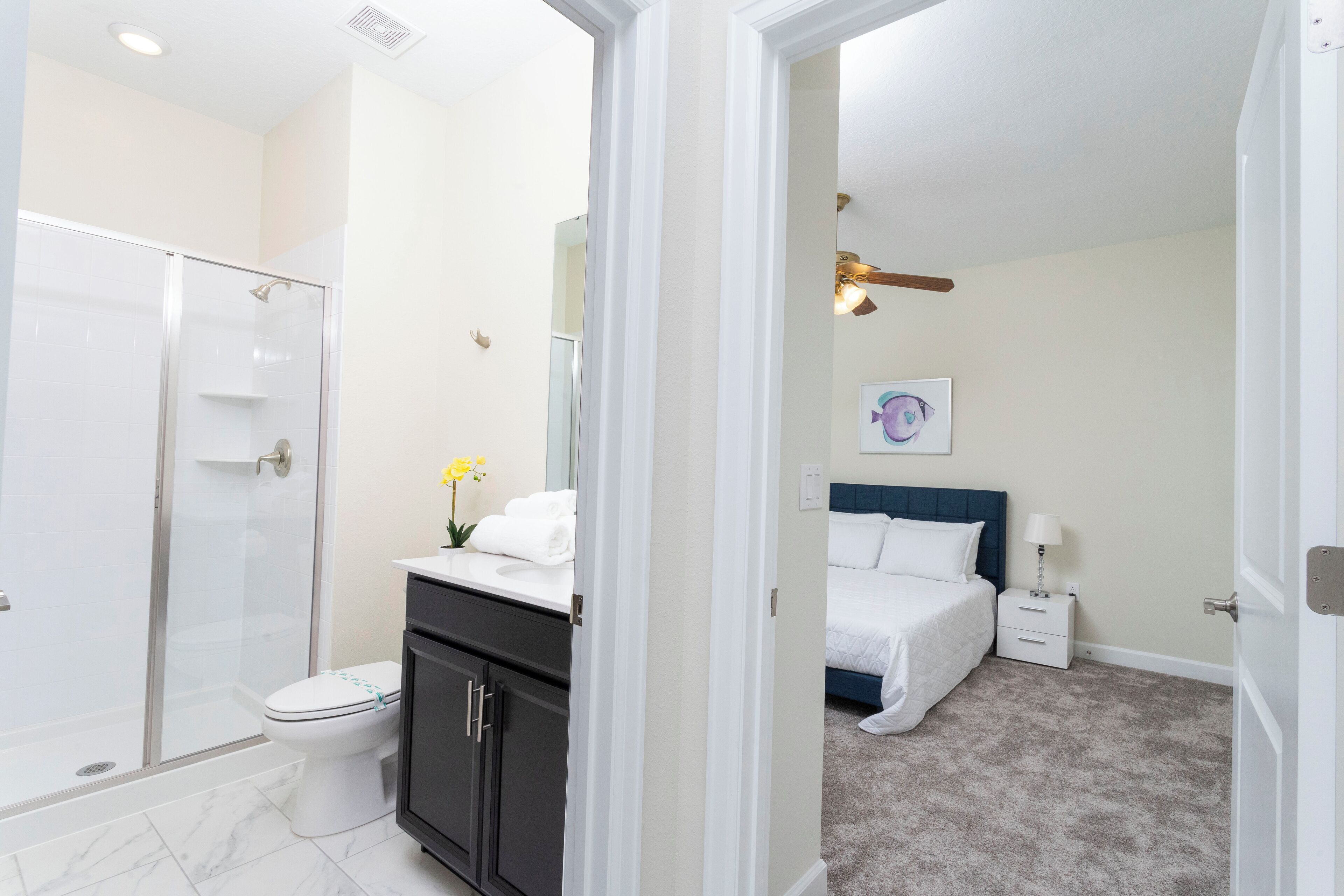 A modern bathroom with a glass-enclosed shower, a white toilet, and a black vanity with a mirror.