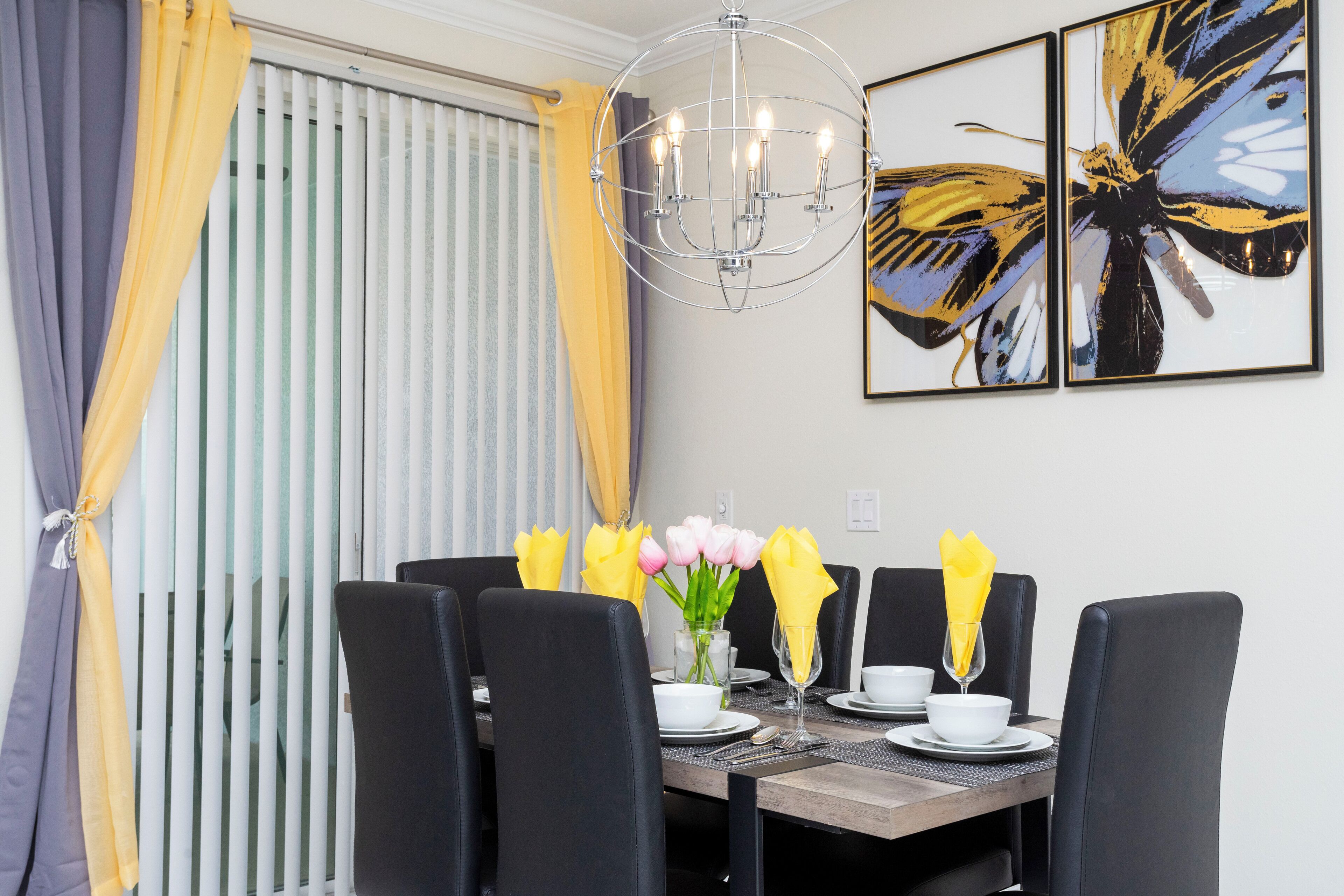 Een eetruimte met een tafel voor vier personen, zwarte stoelen, een kroonluchter en kunst aan de muur.