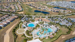Vista aérea de una zona residencial con varias piscinas, campos de golf y un gran parque central.