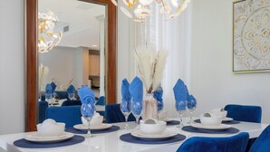Une table à manger dressée avec de l’assiette blanche, des serviettes bleues et un vase rempli de fleurs blanches.