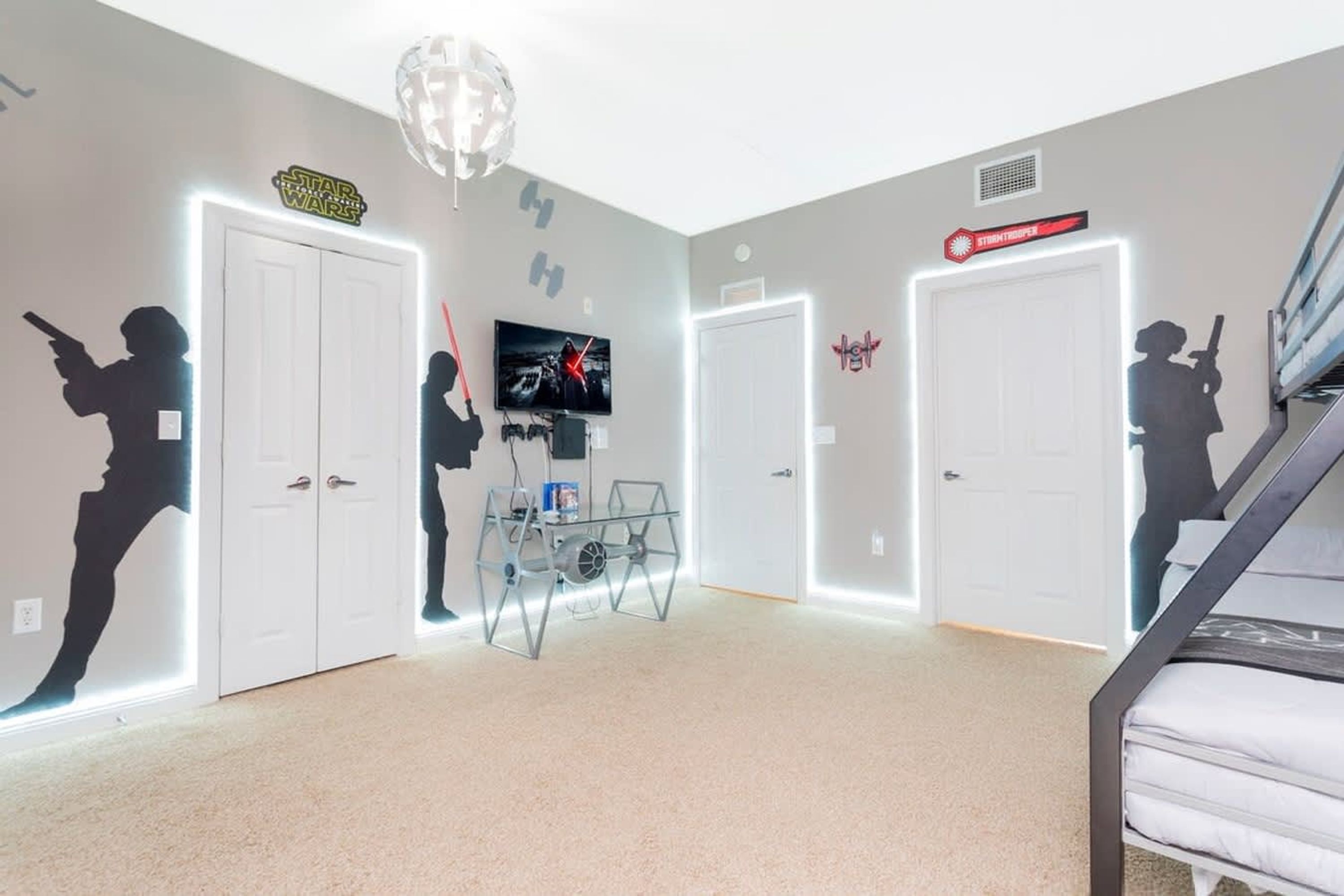Una stanza con decorazioni murali a tema Star Wars, una lampada a soffitto, un televisore e un letto a castello.