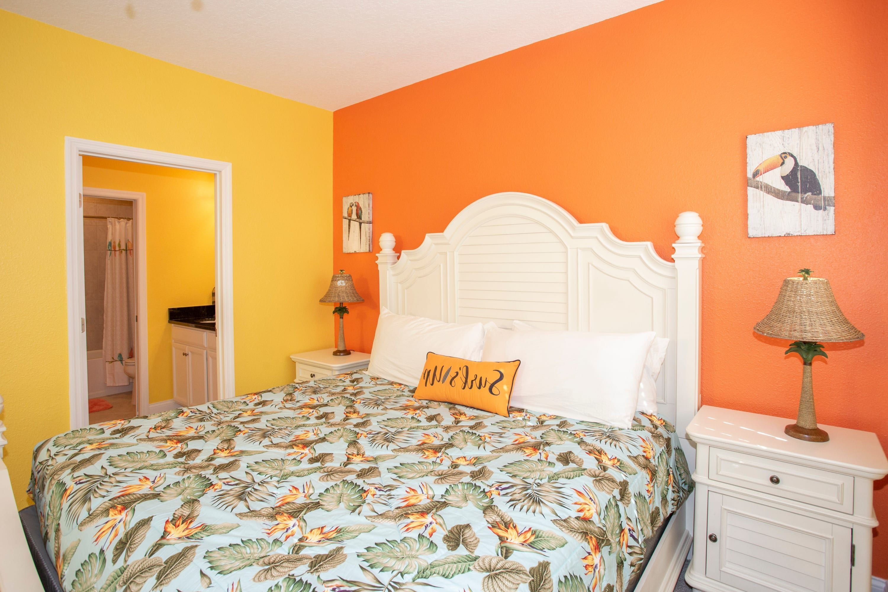 A bedroom with a bed, nightstands, a lamp, and a door leading to another room.