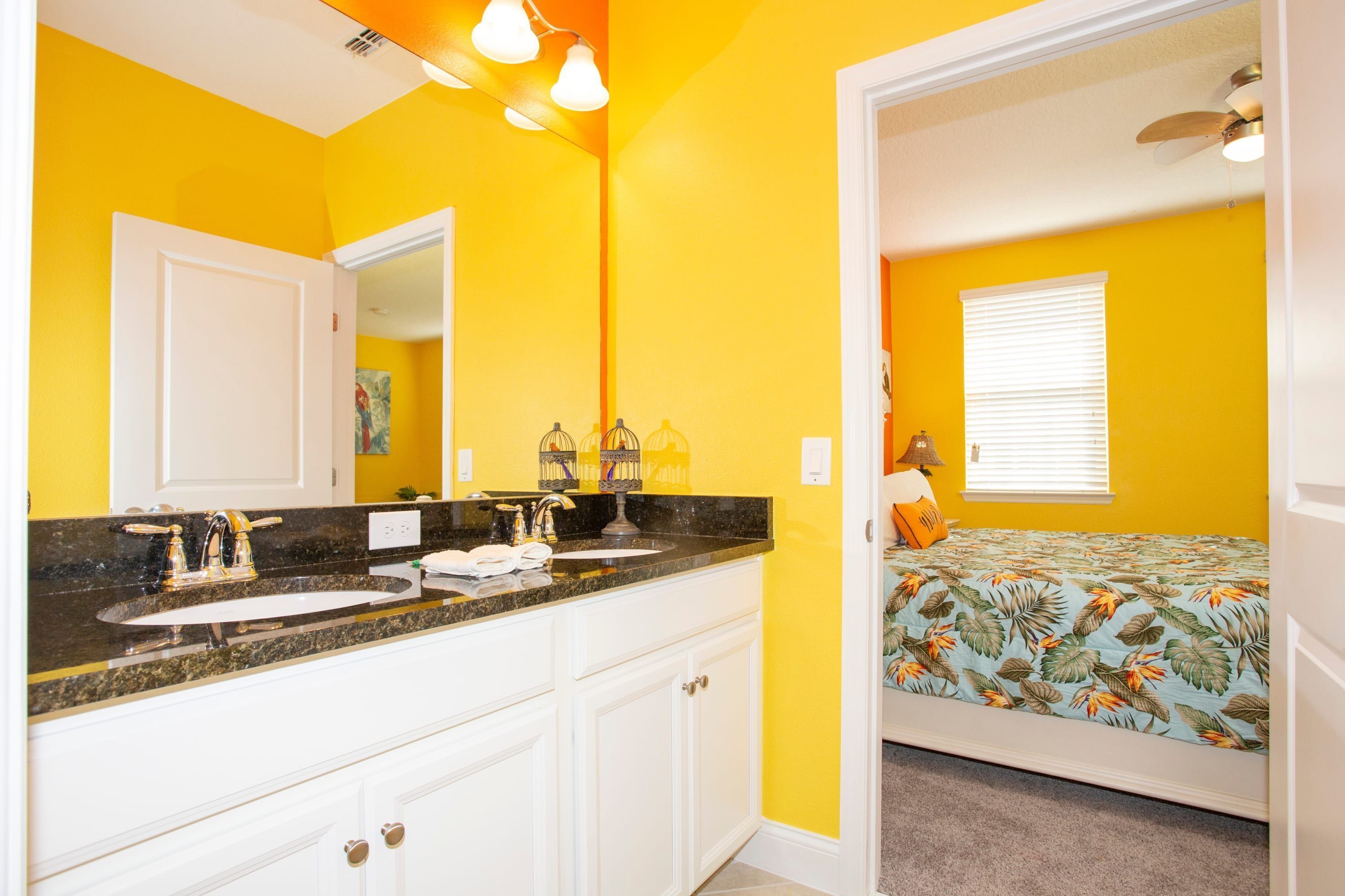 A bathroom with a double sink, white cabinets, and a mirror.