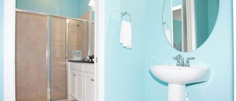 A bathroom with a shower, a sink, and a mirror.