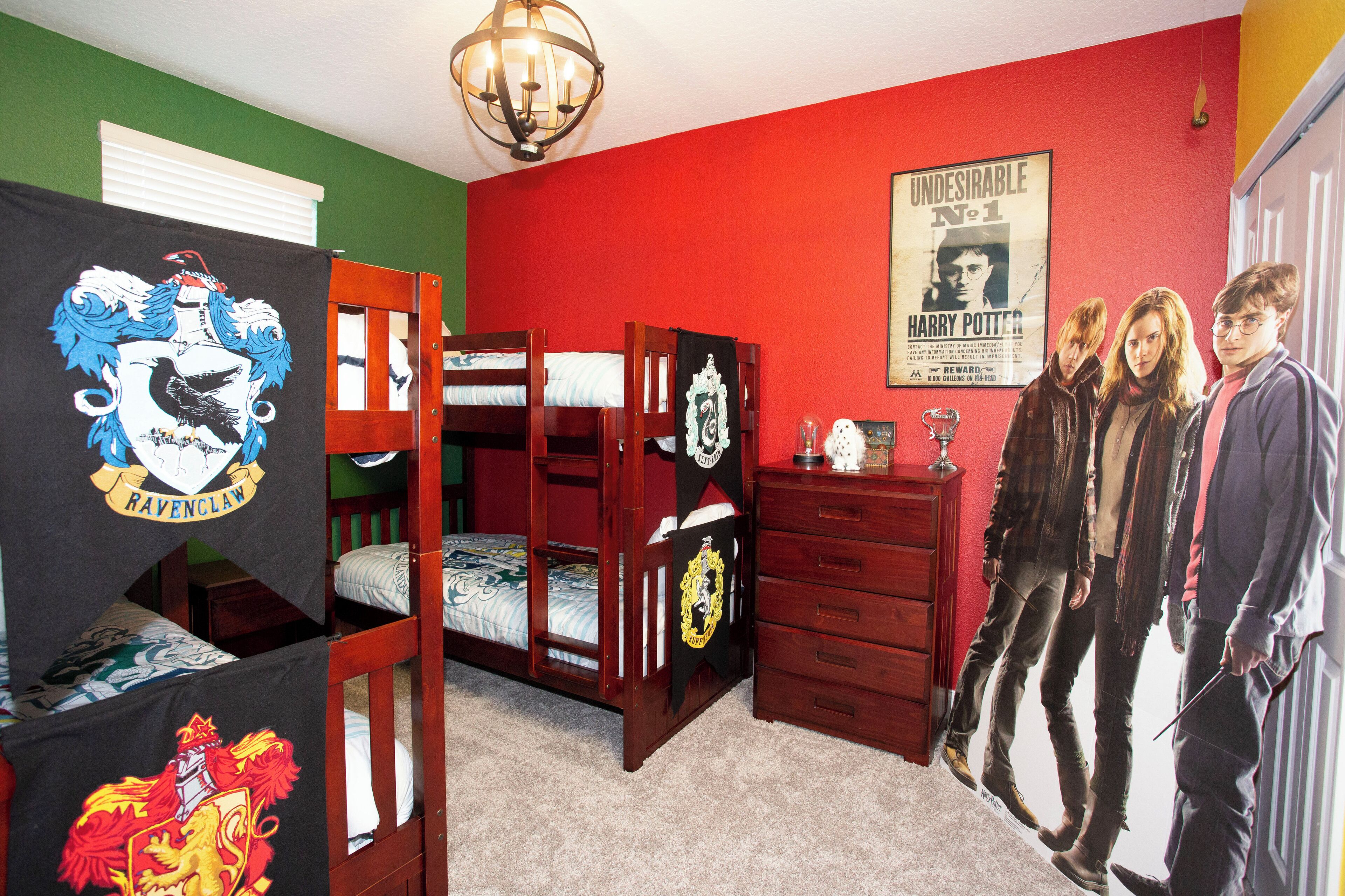 A room with bunk beds, a dresser, a poster of Harry Potter characters, and a chandelier.