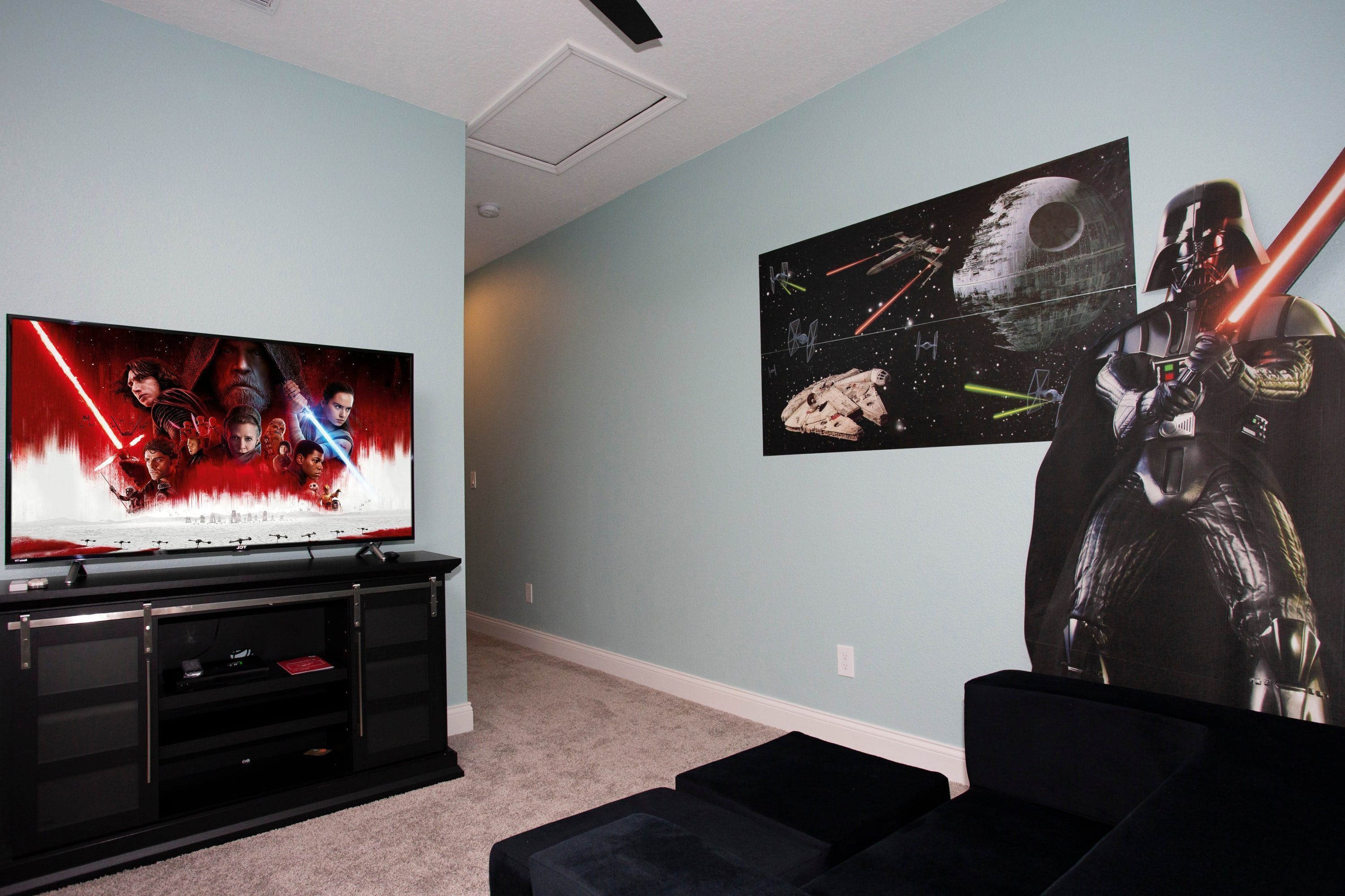 A room with a TV, Star Wars posters, and a Star Wars-themed wall art.