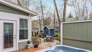 Ein Garten mit Whirlpool, einer Holzterrasse und einer Terrasse mit Gartenmöbeln.