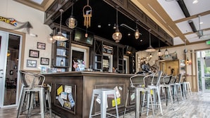 A bar area with a wooden counter, metal stools, and pendant lighting. - Festival Resort 5 Bd Home w Screened Pool Close to Disney 174 (Davenport)