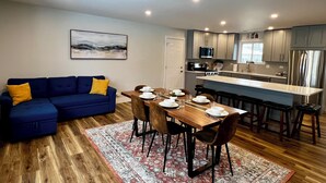 Una cocina moderna con armarios grises, microondas integrado y refrigerador de acero inoxidable.
