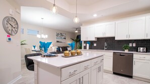 A modern kitchen with white cabinets, a central island, and a dishwasher. - Luxurious 3Bd 8 Guests Storey Lake Resort Close to Disney 201 3131 (Kissimmee)