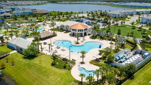 A resort with a central pool, multiple buildings, and a large body of water in the background. - Luxurious 3Bd 8 Guests Storey Lake Resort Close to Disney 201 3131 (Kissimmee)