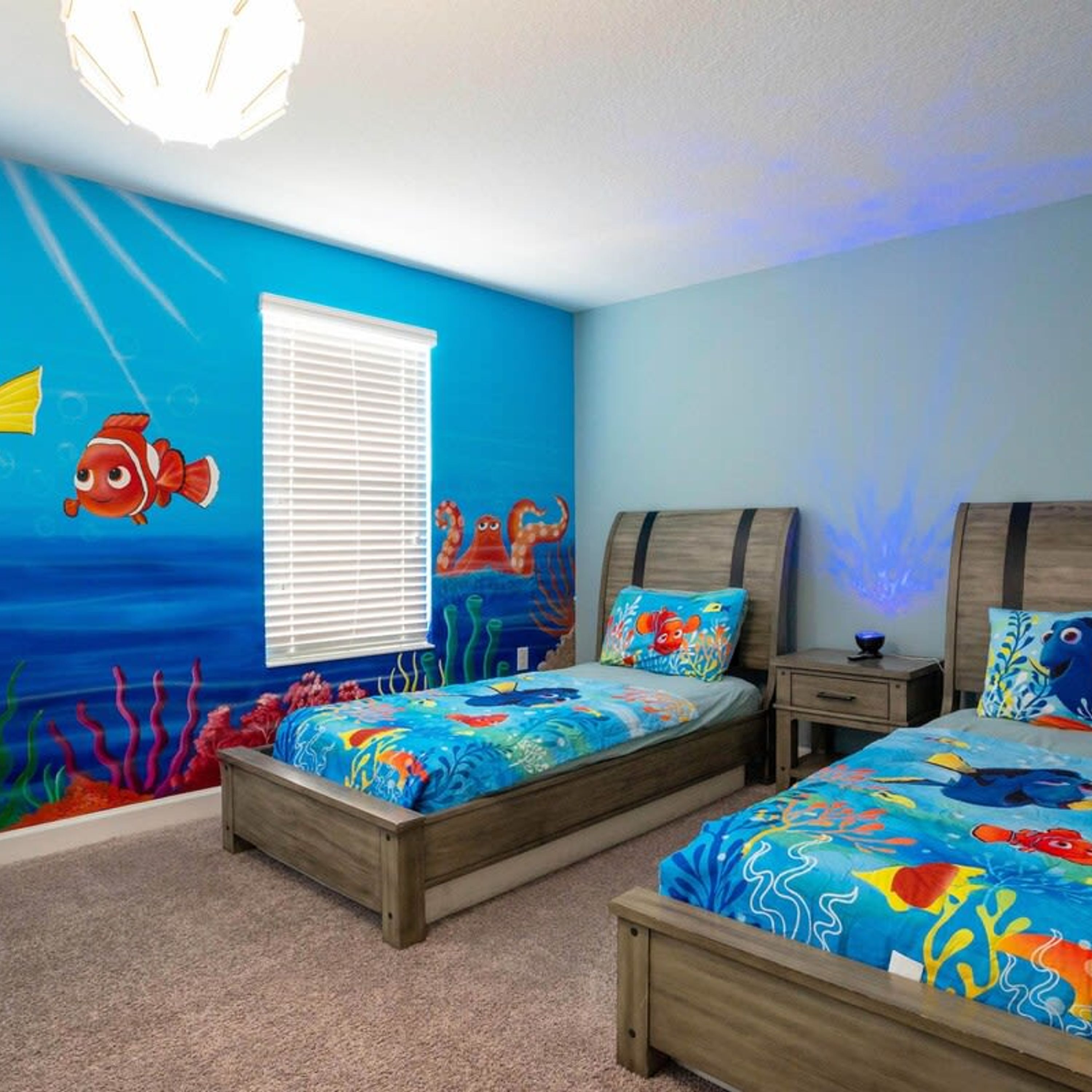 A bedroom with two beds, a window, and a mural of an underwater scene.