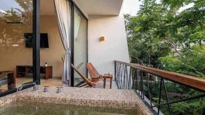 A balcony with a hot tub, a wooden chair, and a small table. - Luxurious Apartment With Jacuzzi Privado (Tulum)