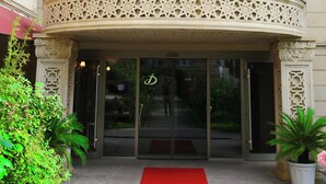 A hotel entrance with a red carpet, ornate balcony, and multiple national flags. - Deluxe Hotel Ganja (Ganja)