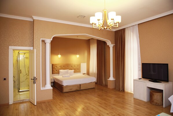 A hotel room with a large bed, a television, and a desk.