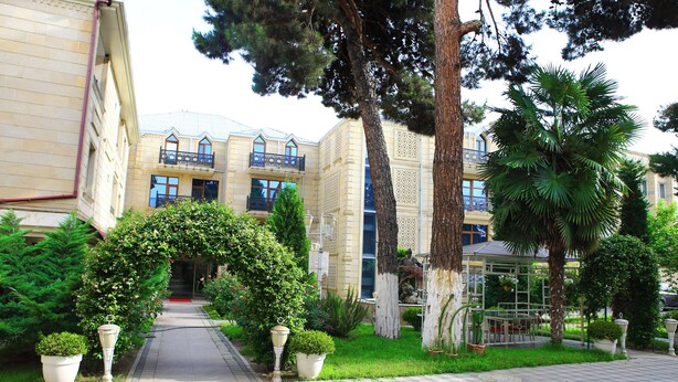 A pathway leading to a building with a balcony and a glass structure. - Deluxe Hotel Ganja (Ganja)