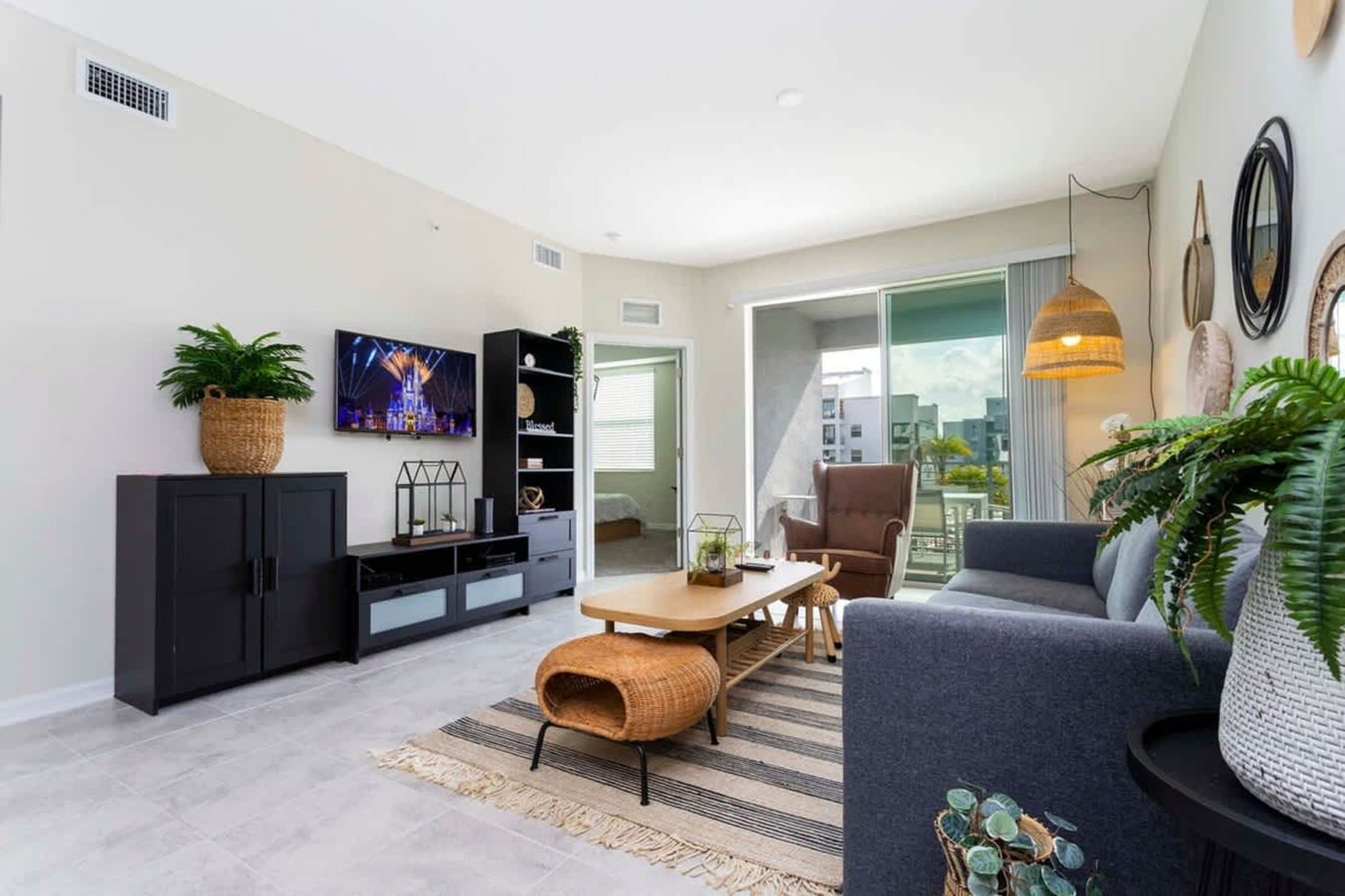 A modern living room with a sofa, TV, and a dining area with a table and chairs.