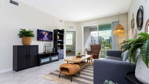 A modern living room with a sofa, TV, and a dining area with a table and chairs.