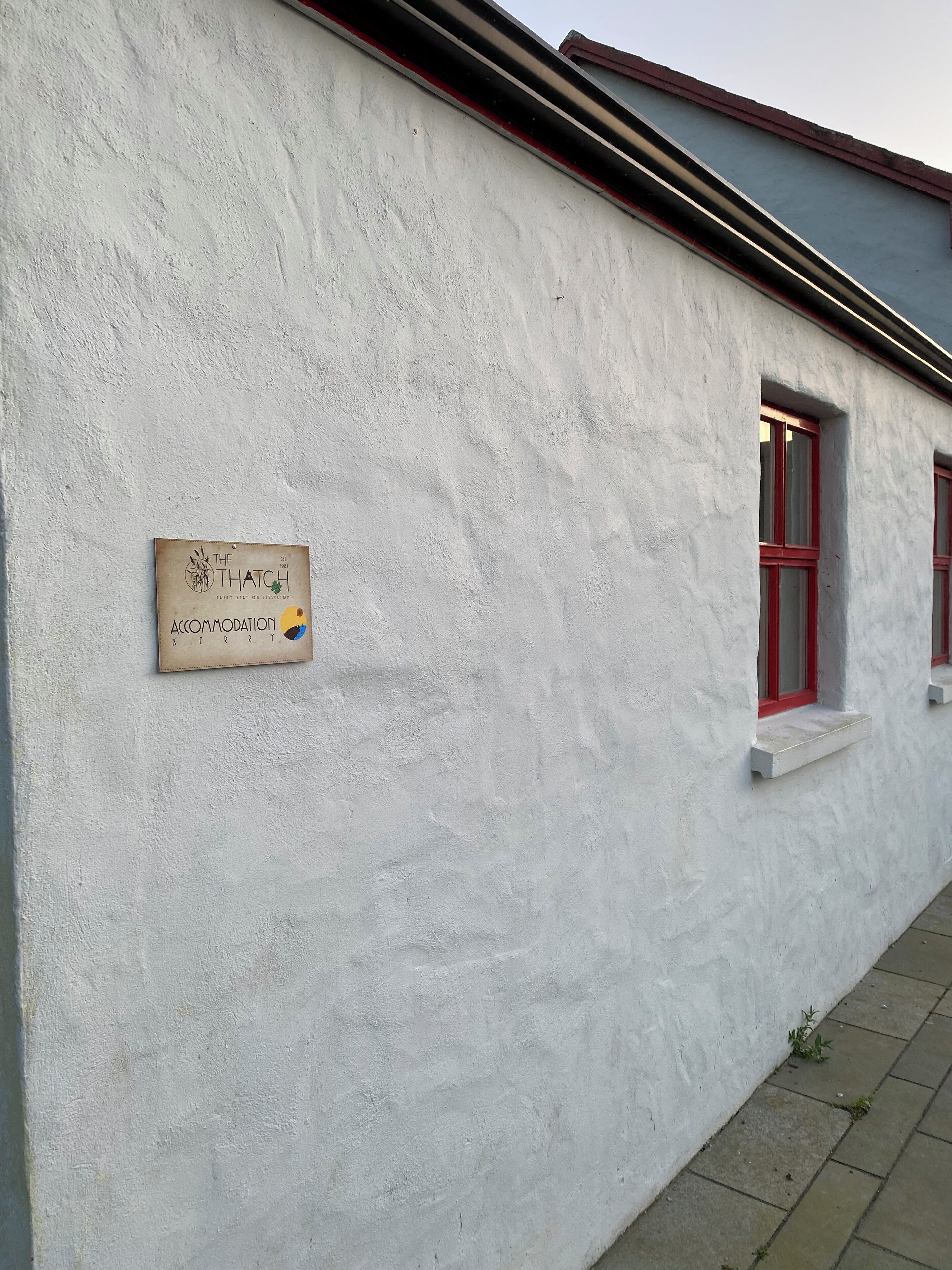Fachada de un edificio con un cartel que indica "The Thatch Accommodation".