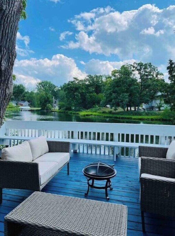 Enjoy a peaceful lakeside retreat with a serene view of lush greenery from this outdoor deck.