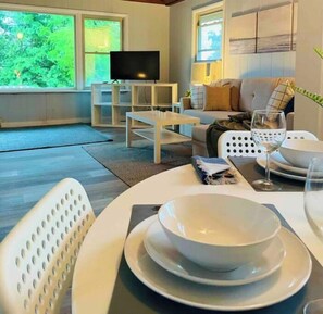Relax in this stylish living room with a flat-screen TV, comfortable sofa, and dining area for two.