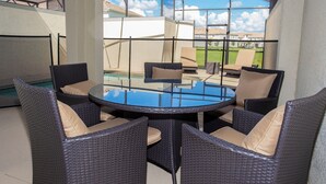 A glass-enclosed patio with wicker furniture and a pool. - Four Bedroom Storey Lake Resort Close to Disney w Pool 3063 (Kissimmee)