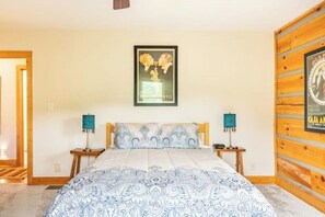 Une chambre à coucher comprenant un lit, deux tables de chevet, une affiche accrochée au mur et un lambris en bois.