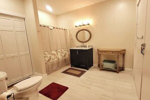 Un baño con inodoro, lavamanos, tocador, ducha y espejo.