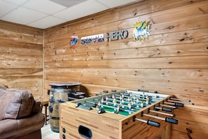 Relax in a warm, inviting space with a foosball table, leather sofa, and rustic charm.