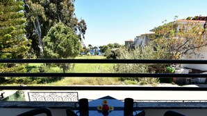A balcony with a table and chairs, overlooking a grassy area with trees and buildings in the background. - Tahir Ağa Hotel Datça (Datça)