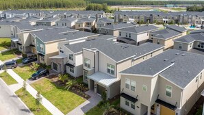 A residential area with modern houses, a paved driveway, and a visible street. - Gorgeous 5Bd Single Family w Pool Storey Lake 2767o (Kissimmee)