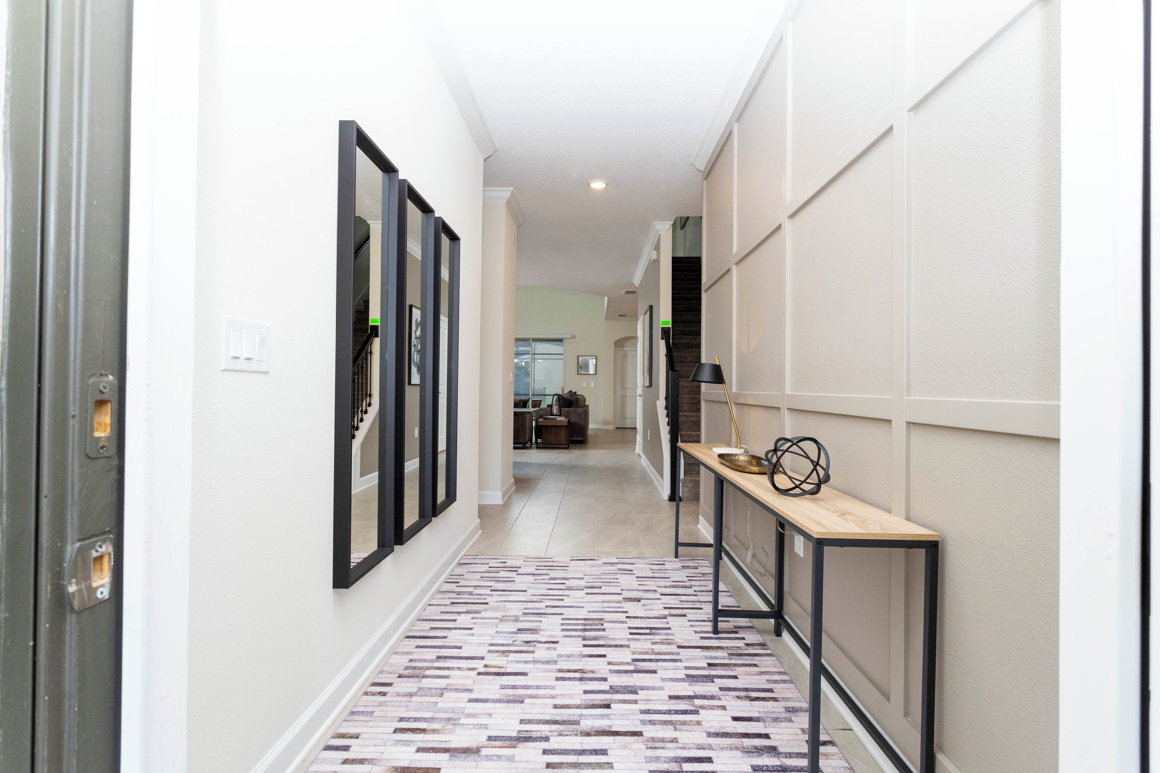 A hallway with a patterned floor, a wooden bench, and a door with a metal handle.