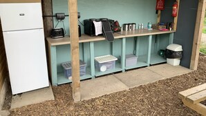A compact kitchenette with a refrigerator, toaster, coffee maker, and storage shelves. - Double Bell Tent Farm Stay (Loughborough)