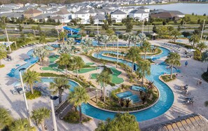 A golf course with a pool, palm trees, and a view of houses in the background. - Gorgeous 5 Bd Home Close to Disney Storey Lake Resort 2734 (Kissimmee)