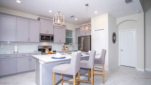 A modern kitchen with grey cabinets, stainless steel appliances, and a marble floor. - Gorgeous 5 Bd Home Close to Disney Storey Lake Resort 2734 (Kissimmee)