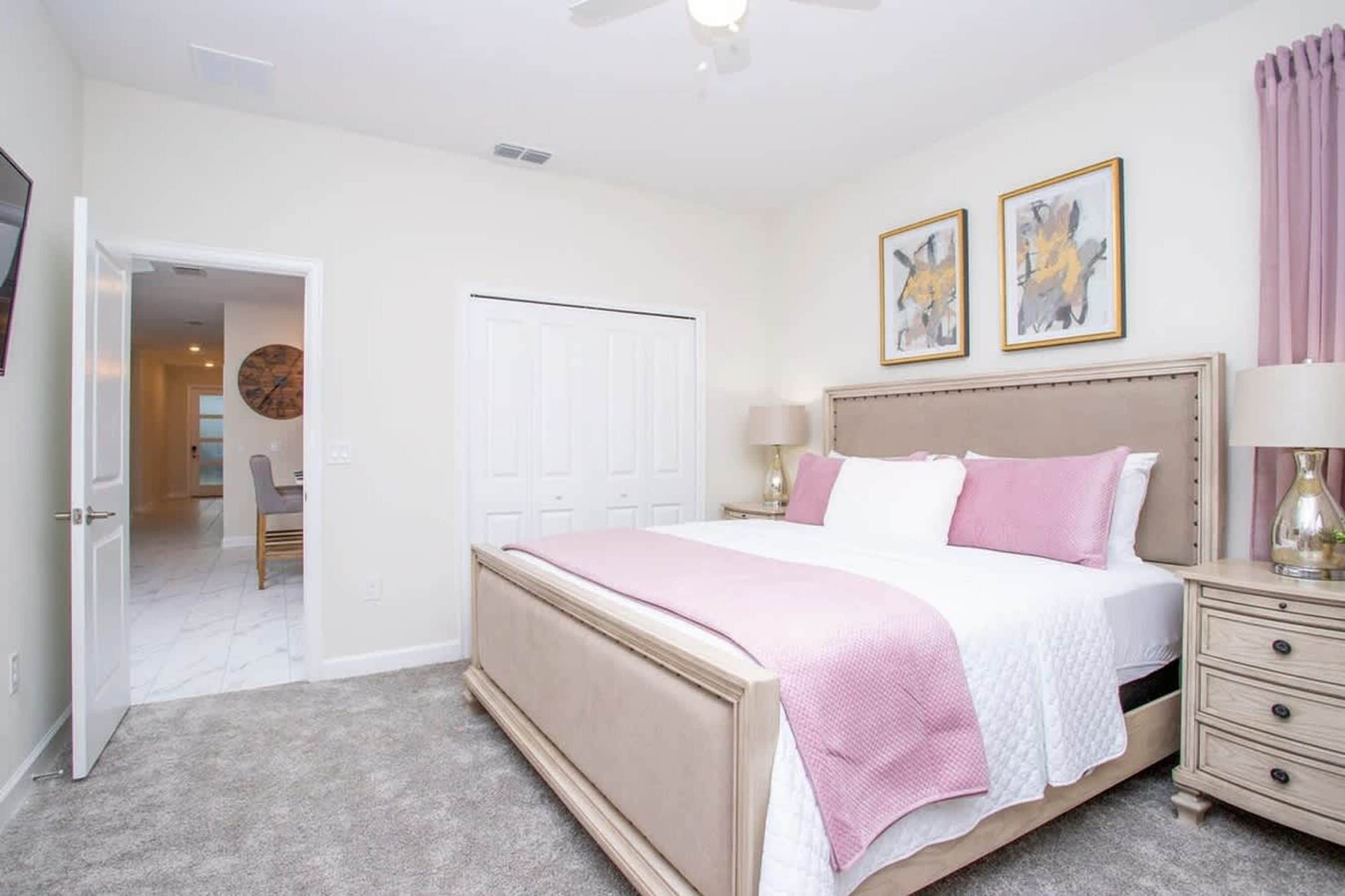 A bedroom with a bed, bedside tables, a door, and a ceiling fan.