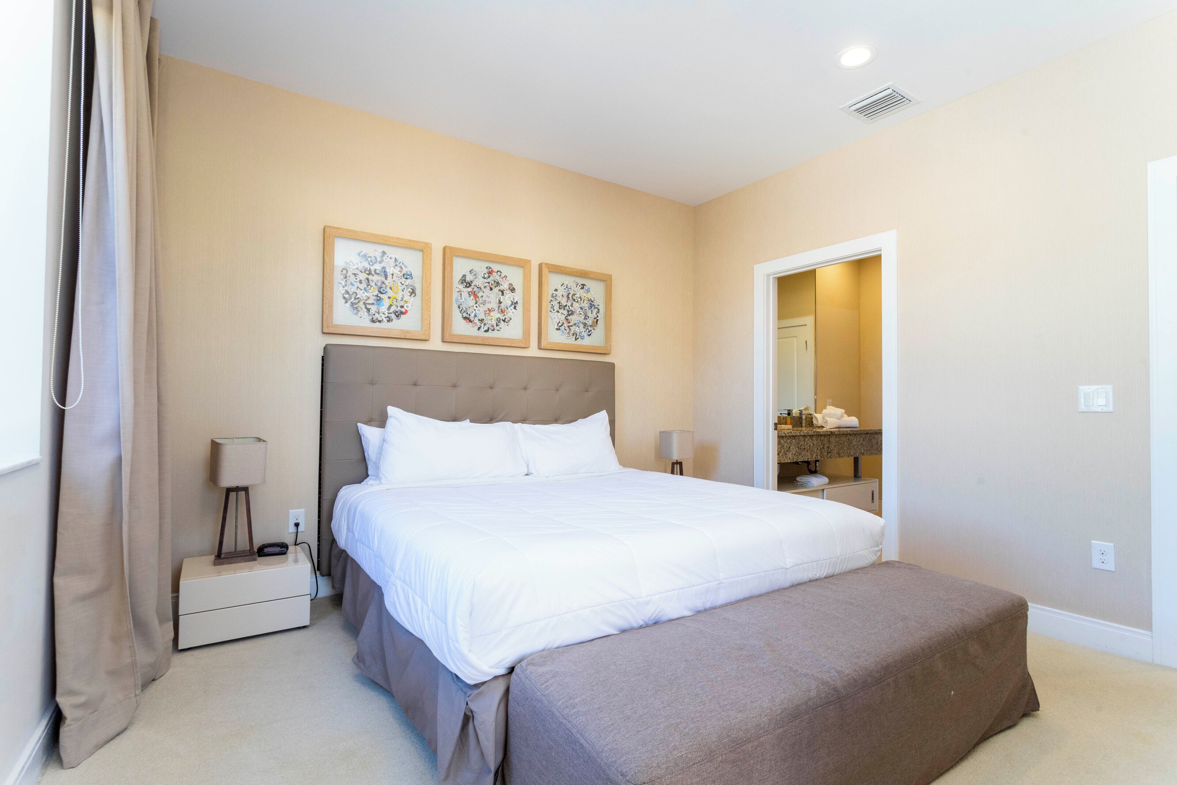 A neatly arranged bedroom with a large bed, bedside tables, and a mirror.