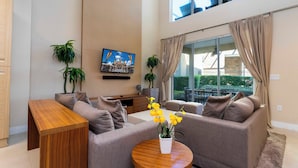 A modern living room with a sofa set, a wooden coffee table, and a TV mounted on the wall. - Gorgeous 4 Bd Close to Disney Magic Village 3114 (Kissimmee)