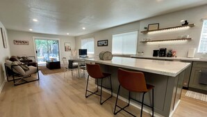 A modern kitchen with a central island, bar stools, and a dining area with a sofa and chairs. - Prime Location, Downtown Murphys (Murphys)