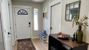 A hallway with a wooden floor, a rug, a bench, a small table with a vase, and a door with a window. - Prime Location, Downtown Murphys (Murphys)
