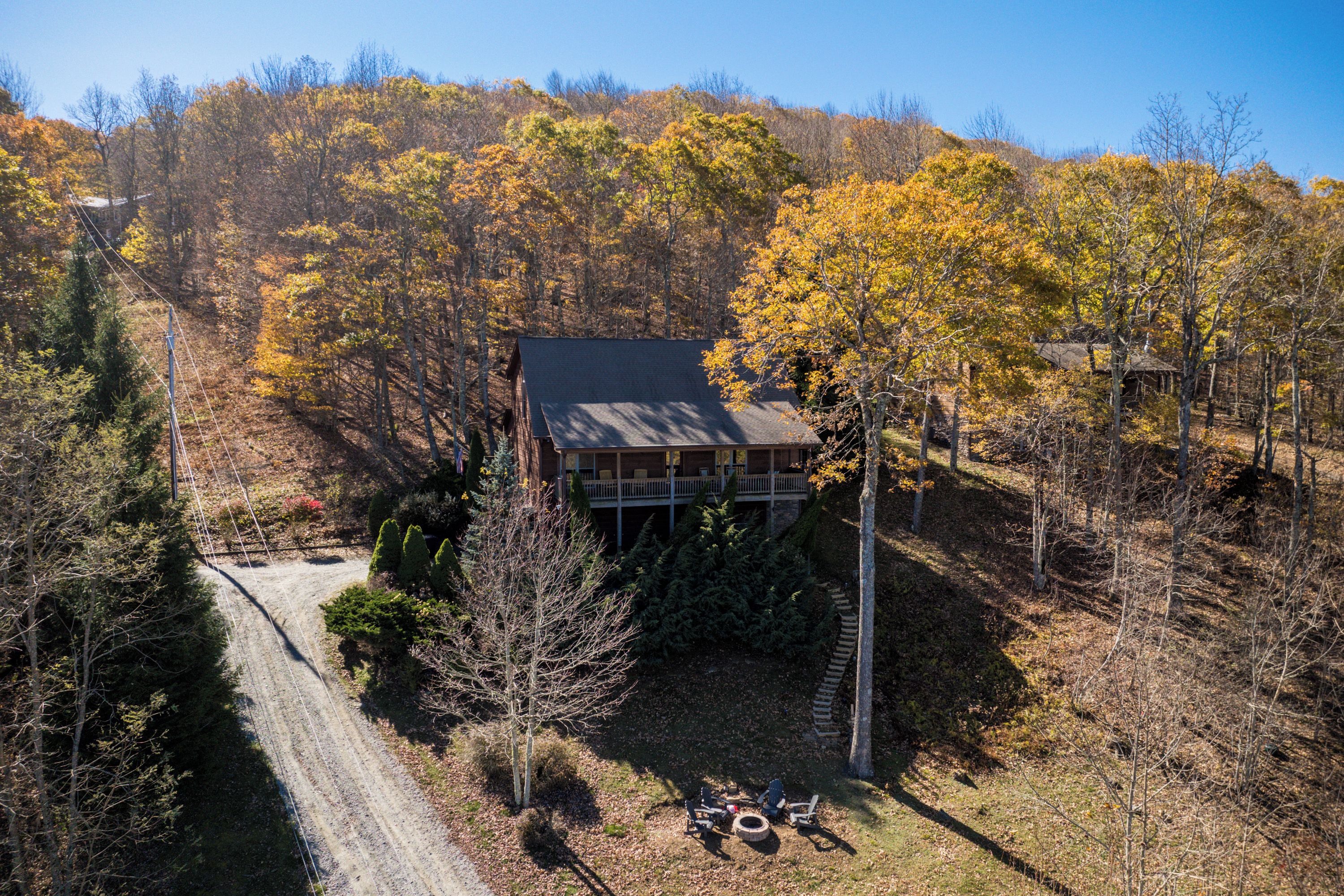 A cabin surrounded by autumn foliage, with a dirt path leading to the entrance.