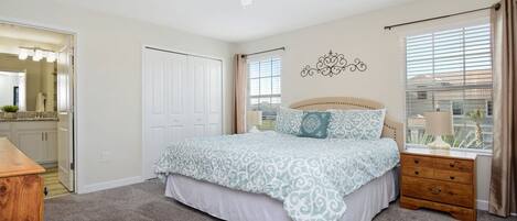 A bedroom with a bed, nightstand, and a window with curtains.