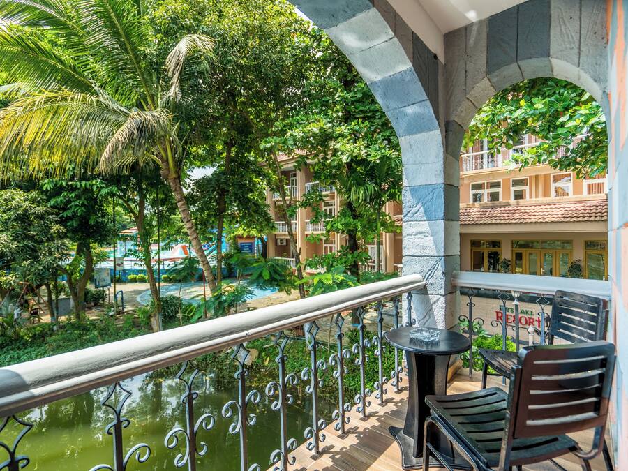 A balcony with a view of a pool and greenery, a table, and a chair.